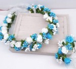 Blomsterkrans med blomster/roser i hvid/blå og silkebånd med lille corsage